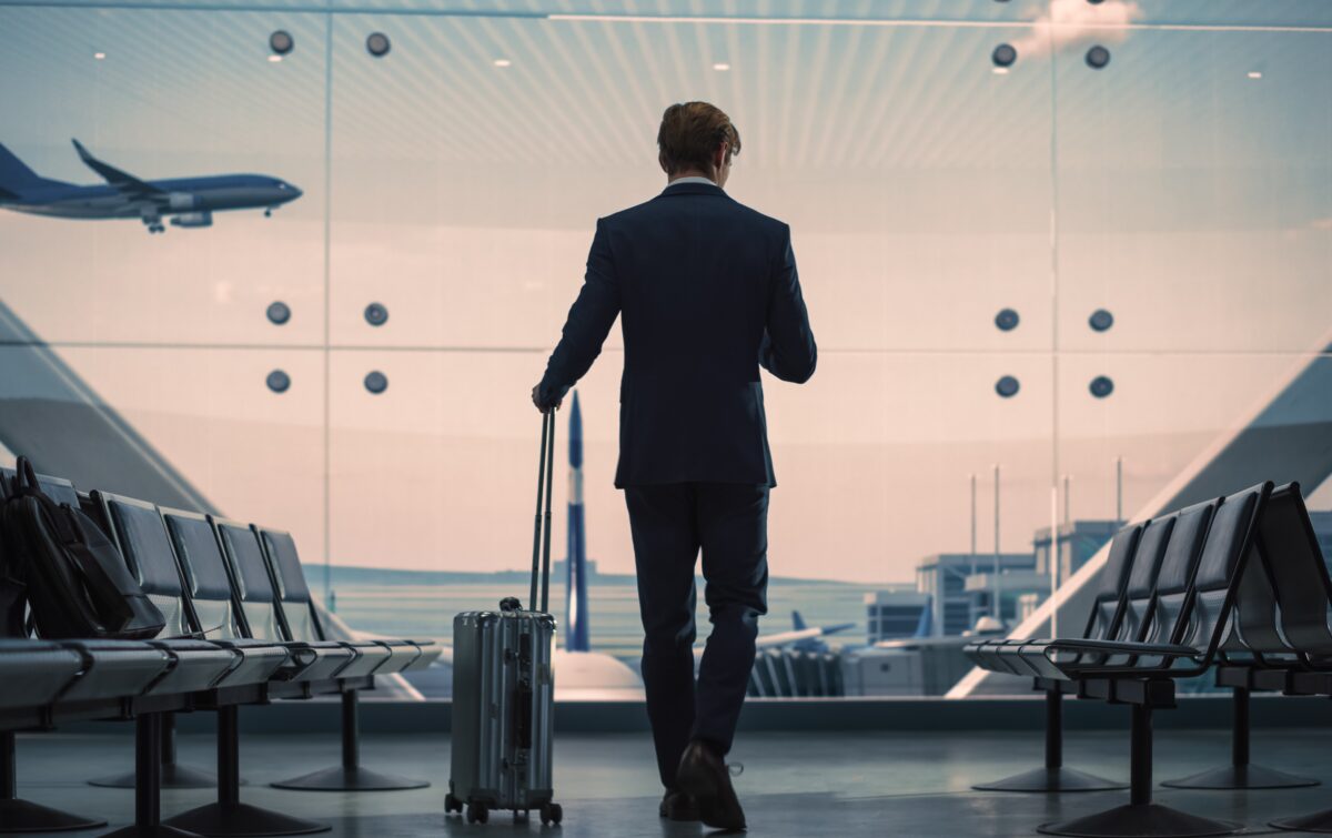 Airport,Terminal:,Businessman,With,Rolling,Suitcase,Walks,,Uses,Smartphone,App